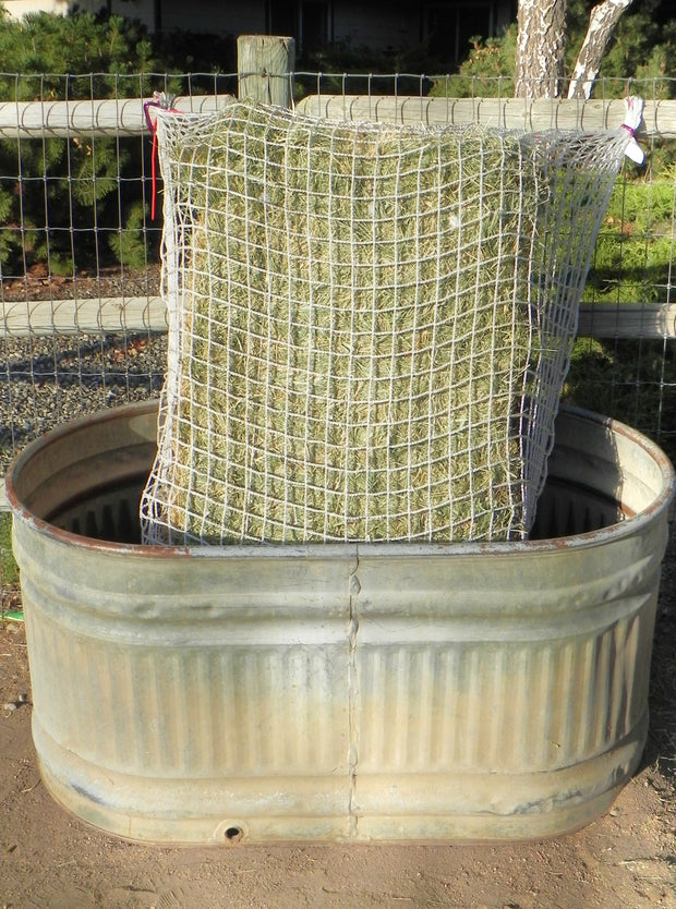 Freedom Feeder 125 lb 3-string bale net, slow feeder in tub on fence